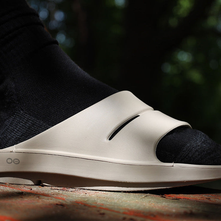 OOFOS OOahh Slide — Nomad, side close-up on foot #Colour_Nomad
