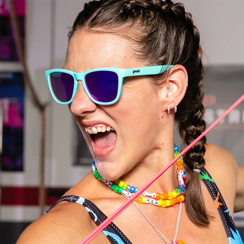 goodr OG Electric Dinotopia Carnival sunglasses, sky blue frame with lavender lenses — styled product view