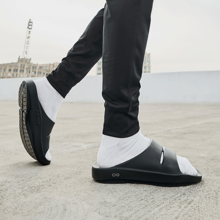 OOFOS OOahh Slide — Black, worn standing #Colour_Black